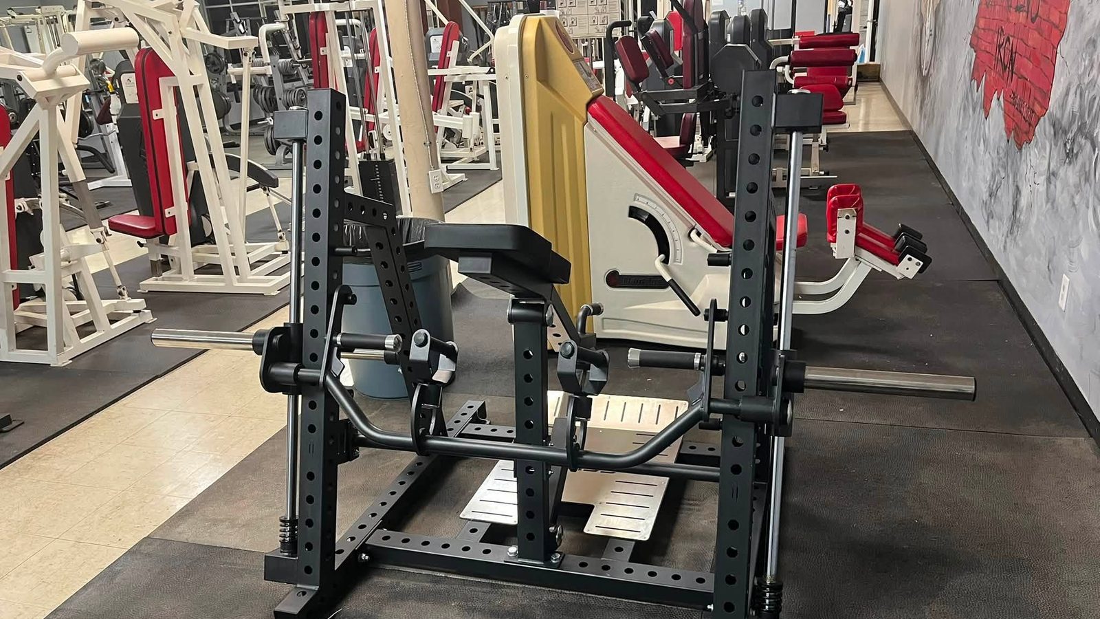 Wide view of the Iron Forge Fitness strength floor showing plate-loaded machines, leg press and rubber flooring
